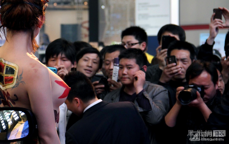 4月6日，在郑州春季车展一家名车展台前，一名上半身全裸的美女模特展示人体彩绘艺术。.jpg