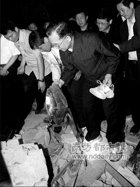 Premier Wen Jiabao picks up schoolbag and shoes that students left over from the ruins, with a heavy
