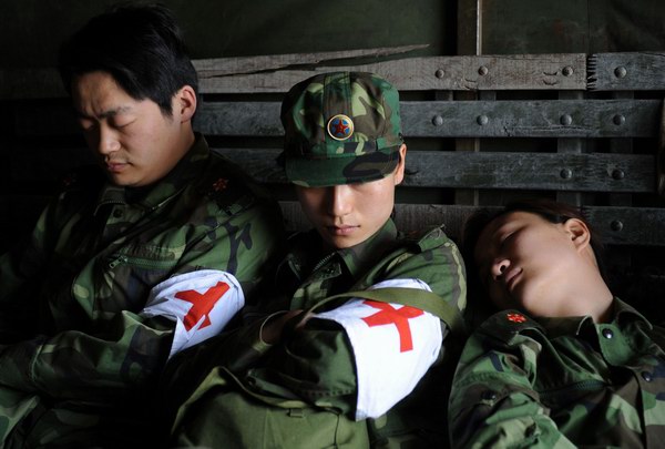 5月14日，3位前往青川县关庄镇地震灾区的总后勤部专业应急医疗队队员在长途跋涉途中休息。  ...