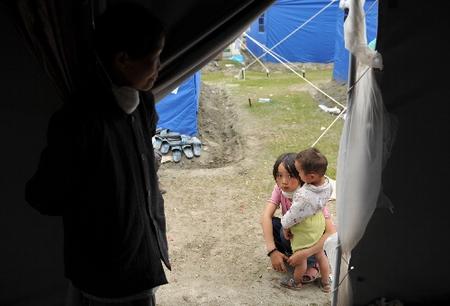 10岁的王永霞在北川县地震灾区临时安置点帐篷外照看妹妹.jpg