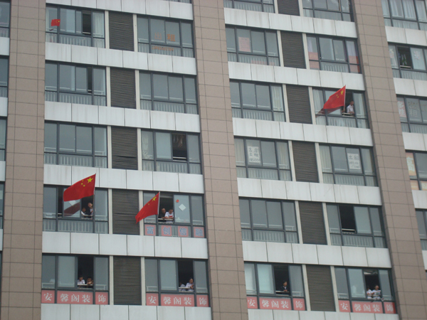 鼓楼公园对面的大楼上已经很多人了，窗户外也伸出很多国旗。